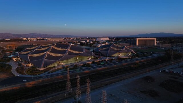 Aerial view of the sprawling Googleplex campus alongside the iconic Hangar One with its distinctive shape, contrasted against the twilight sky, Mountain View, California, United States.