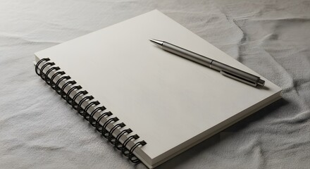 A spiral bound notebook with blank pages sits on a textured gray surface, a pen resting on top. The scene is clean and minimal, suitable for a variety of uses.