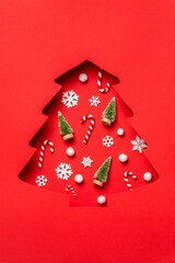 Christmas tree cutout on red background with white snowflakes inside.