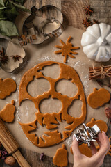 Making cookies for Halloween top view by woman hands. Cut out cookies from dough in form of pumpkin and spider