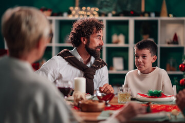 Family celebrating christmas dinner at home, father and son sharing a moment