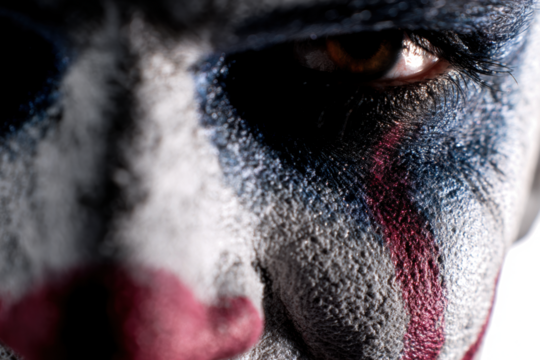 Close-up of a clowns face with dramatic makeup intense gaze creating a sense of unease and mystery