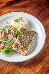 Salmon fish fillet baked, rice, green beans and tomatoes in lunch bowl. Healthy food, top view