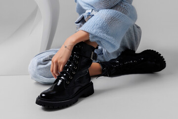 Stylish black lace-up boots showcased alongside casual blue outfit in modern indoor setting