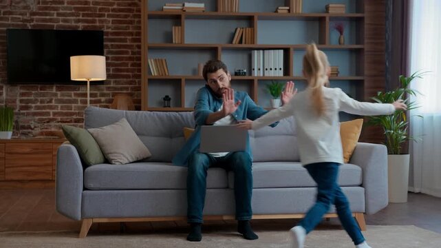 Family at home freelancer dad working laptop talking phone active child running around sofa hyperactive playful kid girl daughter run noisy disturbing father from multitasking work stressed parenting