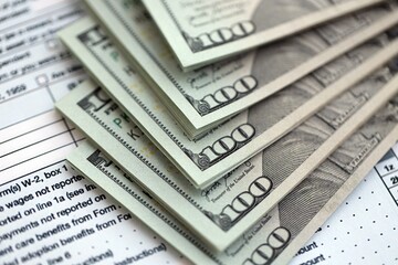 Big amount of United States dollar bills on table with 1040 individual income tax return form....