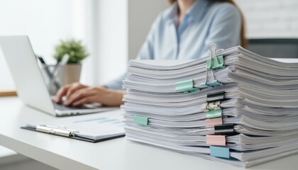 Business woman working on laptop computer with stack of paper document for searching and checking document on folder paper at busy work on desk office, close up