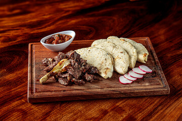 Two cuts of beef, accompanied by cheese-stuffed chiles güeros, grilled cambray onions, guacamole, refried beans, handmade tortillas, chirmoles and chimichurri