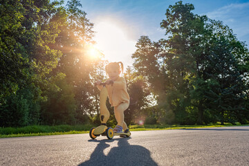 Child scooter riding. Girl yellow scooter park. Motion day lifestyle travel.