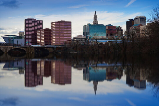 Hartford, Connecticut downtown city skyline with towering skyscrapers and water reflections on the Connecticut River, an urban architecture with riverside tranquility in New England.