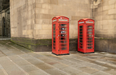 Two Red British Telephone Booths Along a Stone Wall Create a Classic Urban Scene