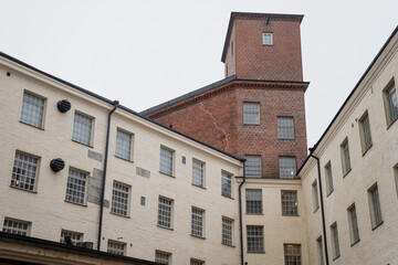 Historic industrial architecture in Tampere Finland with red brick tower and white plaster factory walls representing preserved industrial heritage, adaptive reuse design, and Nordic urban buildings