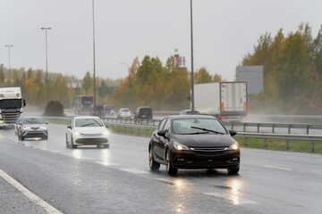 Wet highway scene with multiple cars and trucks traveling in autumn rain showing everyday...
