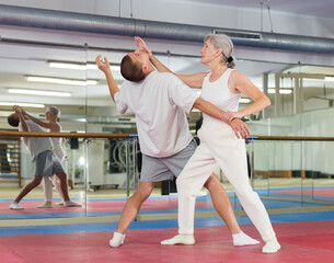 Obraz premium Elderly woman is training with man on the self-defense course in gym