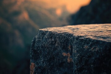 Close-up of a textured dark rock edge, illuminated by a warm glow, set against a soft, blurred, atmospheric background.