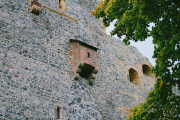 Old stone wall with a brick window. Grey tones, rough texture, weathered detail. A simple building structure, aged stone walls. Perfect for a historical setting.