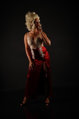 Full length portrait of beautiful woman in a red evening dress and a white wig on a black background