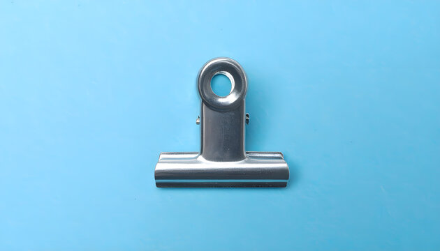 Shiny metal binder clip on a blue background