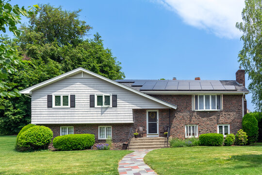Elegant suburban family home with solar panels on the roof and landscaped front yard in Newton, Massachusetts, USA
