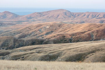 Fototapeta premium The folds of mountains in the morning light, a strip of sea in the background