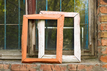 Vintage frames leaned against a weathered brick wall under an old window evoke nostalgia with their textures and rustic charm, creating an authentic and vintage mood, capturing memories of old times.