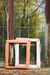 Charming still life of two old wooden frames on a brick windowsill against a worn multi-paned window reflecting greenery, creating a nostalgic and artistic scene, highlighting textures and history.