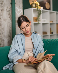 Naklejka premium Woman relaxing at home checking old photo album