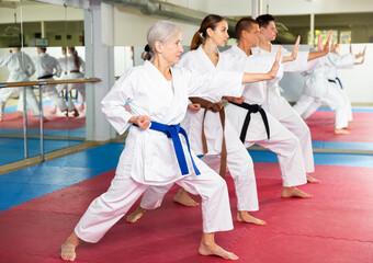 Adult people practicing taekwondo and warming up for training while standing barefoot