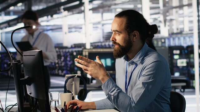 Data center technician discussing with coworker while doing AI software updates. Server room IT specialist and colleague chatting, optimizing infrastructure using artificial intelligence, camera A