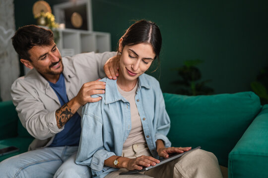 Partner giving relaxing neck massage to woman using tablet