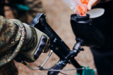 Paintball game, team in camouflage protective uniform with paintball guns and ammunition, strikeball arena battlefield, paintballer aiming and shooting at opponents, airsoft players match tournament