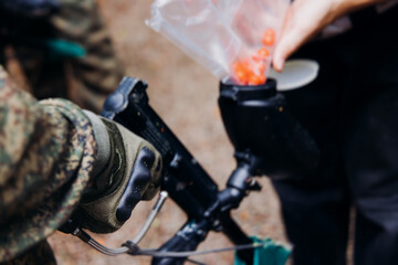 Paintball game, team in camouflage protective uniform with paintball guns and ammunition, strikeball arena battlefield, paintballer aiming and shooting at opponents, airsoft players match tournament