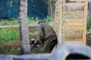 Paintball game, team in camouflage protective uniform with paintball guns and ammunition, strikeball arena battlefield, paintballer aiming and shooting at opponents, airsoft players match tournament