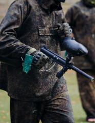 Paintball game, team in camouflage protective uniform with paintball guns and ammunition, strikeball arena battlefield, paintballer aiming and shooting at opponents, airsoft players match tournament