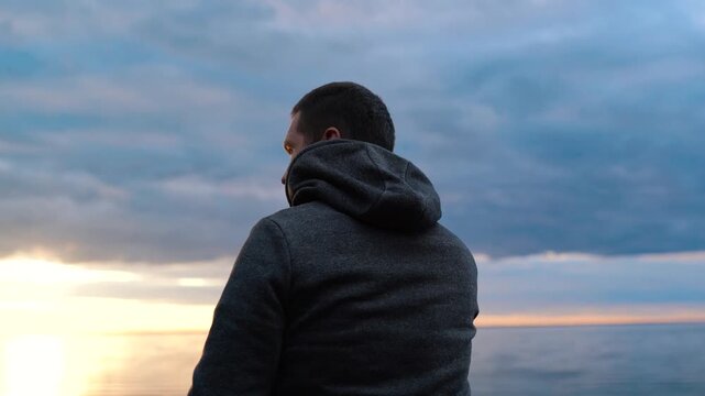 Man Speaks on the phone on a spacious coast near the sea or ocean. Sunset in the water.