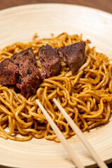 Sliced Steak on Soy-Sauce Noodles on a Wooden Plate
