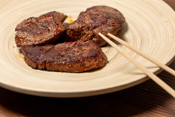 Close-Up of Spice-Seasoned Steak Served on a Wooden Plate with Chopsticks
