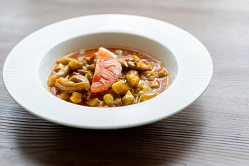 Close-Up of Traditional Okra Dish with Tomatoes on a White Plate on a Wooden Table
