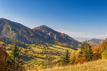 Scenic mountain landscape with autumn foliage under a clear blue sky capturing nature's colorful...