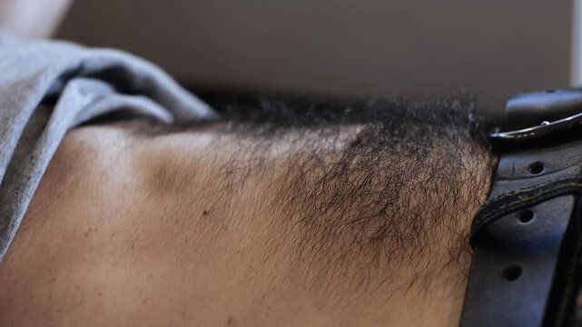 Young man has workout at home or in office during quarantine. Abs training on hairy stomach. Exercising intensive.