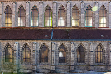 Gothic church exterior with tall arched windows at twilight