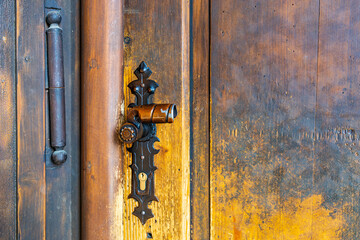 Antique brass door handle on weathered wooden door with rustic details