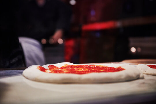 Raw uncooked pizza dough with marinara sauce about to go into the pizza oven 
