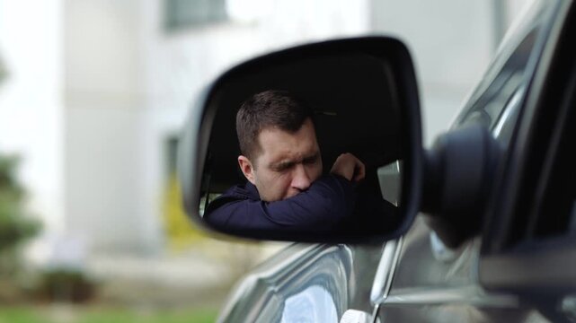 Young man inside car. Slow motion of businessman caughing very hard. A view in side mirror cover mouth with arm and hide it with elbow.