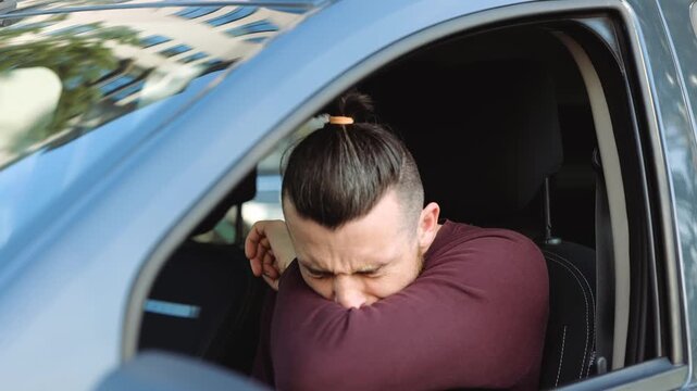 Young man inside car. Guy sit in front and caughing into hand. Suffer from strong pain in sore throat. Sick ill person in car. Caughing in slow motion.