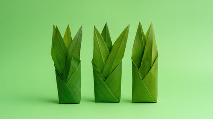 Three green, folded leaves arranged artfully against a bright green background, creating a fresh and vibrant look.