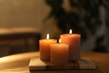 Burning candles on wooden table indoors, closeup. Space for text