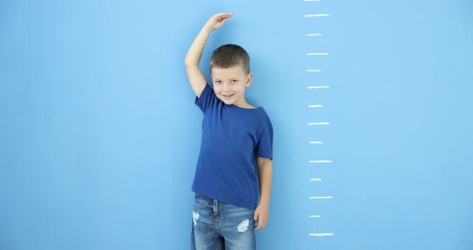 Little boy measuring his height near blue wall