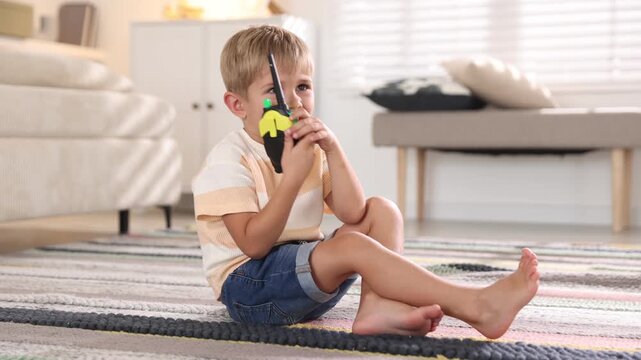 Little boy playing with walkie talkie toy at home