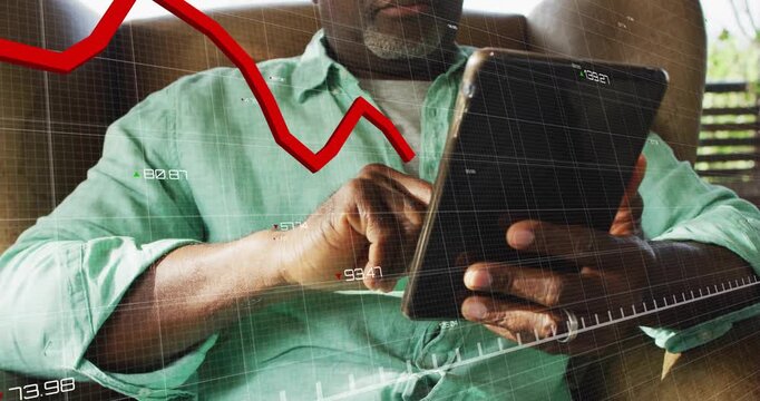 Senior man tapping tablet revealing grid, red finance chart tracking market trend downward, upward